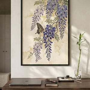 K&ouml;nnte beinhalten: Gerahmter Kunstdruck mit einem Schmetterling auf einem Blauregenzweig mit lila und lavendelfarbenen Bl&uuml;ten. Das Kunstwerk hat eine Vintage-&Auml;sthetik mit neutralem Hintergrund und wird auf einem Holzschreibtisch pr&auml;sentiert.
