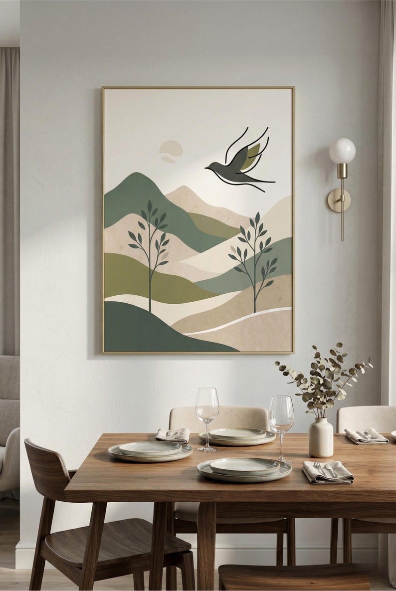 A framed print of a minimalist landscape with green and beige hills, trees, and a flying bird, hanging on a light gray wall above a wooden dining table set for four.