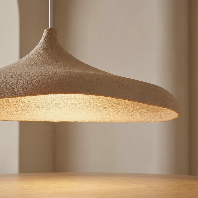 Op de afbeelding: Een set van drie keramische mokken met een gespikkelde, matte afwerking. De mokken zijn in cr&egrave;me, lichtgrijs en donkergrijs. Elke mok heeft een eenvoudig, minimalistisch ontwerp en een afgeronde handgreep.