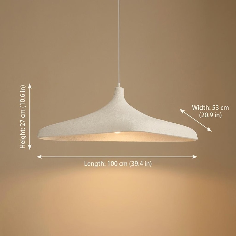 Op de afbeelding: Een witte hanglamp met een brede, ondiepe kap. De lamp is 100 cm lang, 53 cm breed en 27 cm hoog. De armatuur hangt aan een enkele draad en is ontworpen om omgevingslicht te geven.