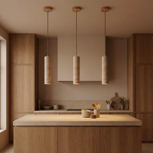 Könnte beinhalten: Drei zylindrische Pendelleuchten mit einer hellbeige steinartigen Textur hängen von der Decke in einer Küche. Die Leuchten sind an dünnen, braunen Kabeln aufgehängt und haben Deckenhalterungen aus Holz. Die Küche verfügt über helle Holzschränke und eine passende Insel.