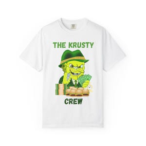 Könnte beinhalten: Weißes T-Shirt mit einem Cartoon-Bild von SpongeBob Schwammkopf mit grünem Hut und Anzug, der Geld und Burger hält. Der Text "THE KRUSTY CREW" ist oberhalb und unterhalb des Bildes in Grün gedruckt.