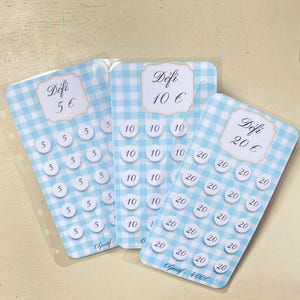 Peut inclure: Trois cartes de suivi d'épargne rectangulaires avec un motif vichy bleu clair et blanc. Chaque carte présente une étiquette centrale avec le texte Défi suivi de 5 €, 10 € ou 20 €, et des rangées d'icônes circulaires avec les valeurs.