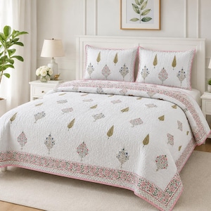 May include: A white quilted bedspread and two matching pillow shams featuring a repeating pattern of small, stylized botanical motifs in shades of green, pink, and blue, finished with a decorative pink and green floral border along the edges.