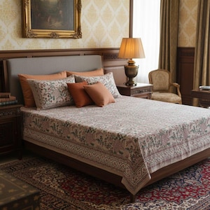 May include: A bedroom with a bed dressed with a patterned beige and green bedspread and pillows. The room has a classic style with a framed painting, a bedside lamp, and a patterned rug. The colour scheme includes beige, brown, and orange.