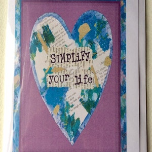 Puede incluir: Una tarjeta morada con una forma de corazón azul y dorado con el texto "SIMPLIFY your life" en ella.