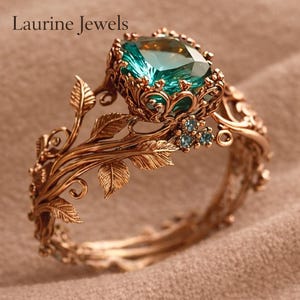 May include: A detailed, antique-style ring with a large, square-cut teal gemstone. The ring features a gold-colored band with intricate leaf and floral designs. The text "Laurine Jewels" is at the top of the image.