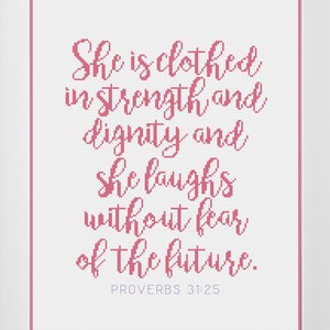 May include: A pink and white framed print with a quote from Proverbs 31:25, "She is clothed in strength and dignity and she laughs without fear of the future."