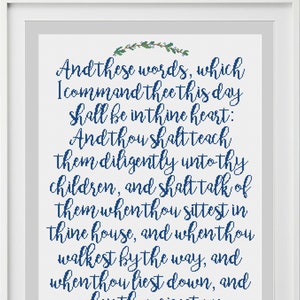 Può includere: Una stampa incorniciata con un designo blu e bianco che presenta un versetto biblico dal Deuteronomio 6:6-7. Il versetto recita: "Queste parole che oggi ti comando, saranno nel tuo cuore; e le insegnerai diligentemente ai tuoi figli, e ne parlerai quando ti siedi in casa tua, e quando cammini per la strada, e quando ti corichi, e quando ti alzi."
