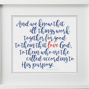 Op de afbeelding: Een ingelijste print met een witte rand. Het kunstwerk bevat een citaat in blauw script, met het woord "love" in rood. De tekst luidt: "En wij weten dat alle dingen medewerken ten goede voor hen die God liefhebben, voor hen die geroepen zijn overeenkomstig zijn voornemen. Romeinen 8:28."