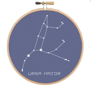 Può includere: Un cerchio da ricamo blu con un contorno bianco della costellazione dell'Orsa Maggiore. Il testo "URSA MAJOR" è stampato sotto la costellazione.