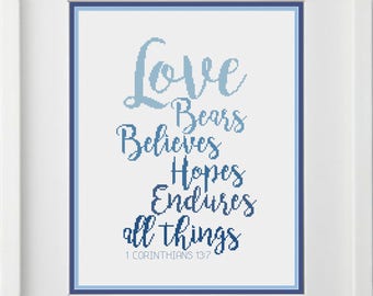May include: A blue and white cross-stitch design with the text "Love bears believes hopes endures all things 1 Corinthians 13:7".