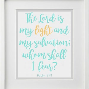 Op de afbeelding: Een ingelijst kruissteek met een turquoise blauwe en oranje tekst die luidt: "De Heer is mijn licht en mijn heil; voor wie zou ik bevreesd zijn? Psalm 27:1"