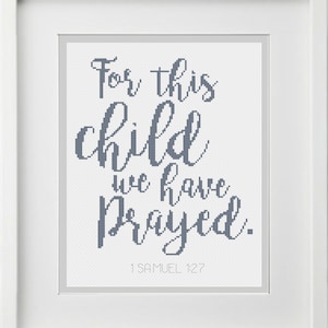 Puede incluir: Un bordado de punto de cruz enmarcado con el texto "For this child we have prayed." y la referencia bíblica "1 Samuel 1:27".