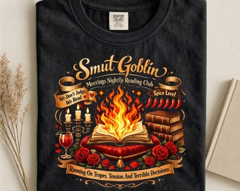 Può includere: T-shirt nero con un design grafico con il testo "Smut Goblin Meetings Nightly Reading Club". Il design include un libro con fiamme, rose, candele e il testo "Running On Tropes, Tension And Terrible Decisions."