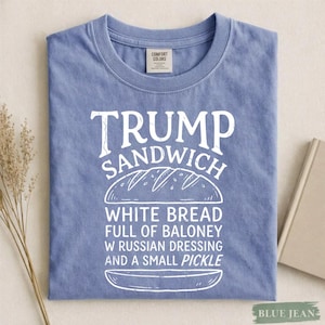 May include: Blue jean-colored t-shirt with the text "TRUMP SANDWICH" in white, along with a graphic of a sandwich. The sandwich text reads "WHITE BREAD FULL OF BALONEY W RUSSIAN DRESSING AND A SMALL PICKLE."
