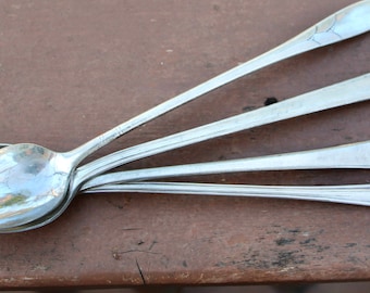 May include: Four silver spoons stacked on top of each other. The spoons have ornate handles with a decorative design.