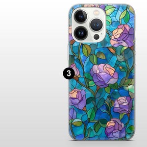 May include: A clear phone case featuring a stained glass design with purple roses, green leaves, and blue background. The case has a glossy finish and covers the back and sides of the phone. The phone case has a triple camera system.