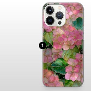 May include: A phone case featuring a floral design with pink flowers, green leaves, and gold outlines. The case has a clear background and a glossy finish. The design is reminiscent of stained glass.