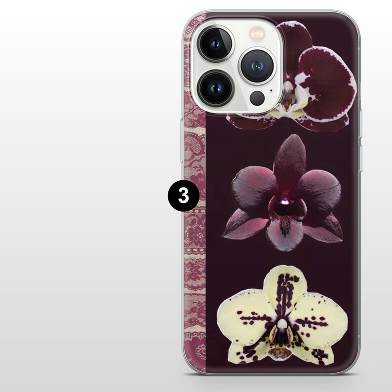 May include: A phone case with a dark background, showcasing three orchid blooms in burgundy and cream. The case has a clear border and a decorative lace pattern on the left. The number "3" is printed on the case.