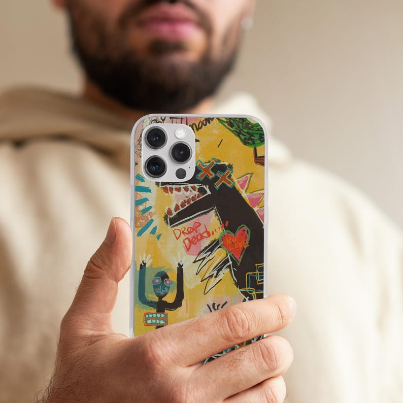 May include: A clear phone case featuring a colorful, abstract design with a yellow background. The artwork includes a black dinosaur-like figure with a red heart, the words "Drop Dead," and a stick figure with raised arms.