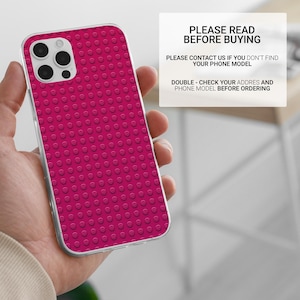 May include: A magenta phone case with a raised dot pattern, held in a hand. The case has a clear border and a camera cutout. Text on a white background reads "PLEASE READ BEFORE BUYING".