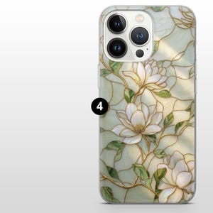 May include: Clear phone case with a floral design. The case features white magnolia flowers with green leaves and gold-colored stems. The background has a stained-glass effect with light green and cream colors. The phone case has a camera cutout and the number 4.