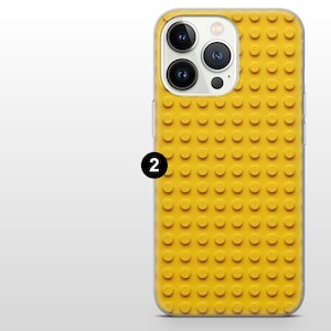 May include: Yellow phone case with a raised, textured design resembling toy building blocks. The case has a clear border and a black number 2 is visible on the side. The case is designed to fit a smartphone.