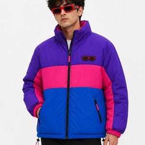 May include: A color-blocked puffer jacket featuring horizontal panels of purple, hot pink, and blue. The jacket has a high collar, a black front zipper, and a small rectangular patch on the chest depicting red-framed sunglasses.