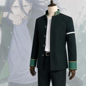 May include: A dark green jacket with a high collar, silver buttons, and green cuffs featuring a stitched diamond pattern. The jacket includes a white horizontal stripe on the left sleeve and is worn over a white shirt and black trousers on a mannequin.