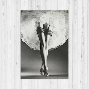 May include: Monochrome image of legs in black lace stockings and high heels, with a white tulle skirt. The legs are crossed at the ankles, and the heels are visible. A classic, elegant aesthetic.