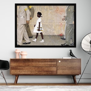 May include: Framed print of a painting depicting a young Black girl in a white dress walking past a group of men in suits. The artwork is set against a textured background with a black frame. The print is displayed above a wooden cabinet.