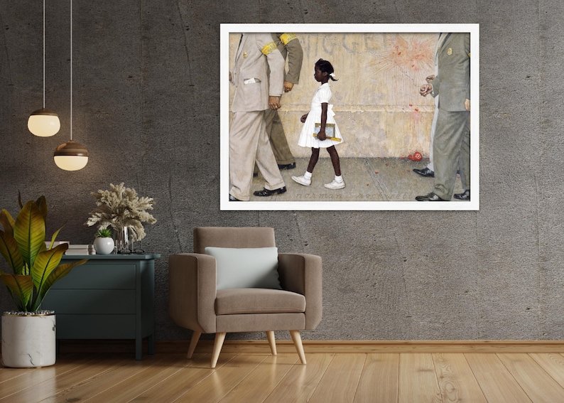 May include: A framed print of Norman Rockwell's painting, "The Problem We All Live With." It depicts a young Black girl in a white dress walking past U.S. Marshals. The artwork is displayed on a gray wall above a brown armchair.