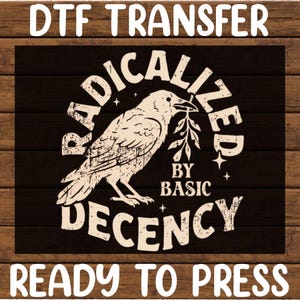 May include: A black and white DTF transfer with a distressed design. The graphic features a raven holding a sprig, surrounded by the words "RADICALIZED BY BASIC DECENCY". The text "READY TO PRESS" is at the bottom.