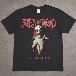 以下が含まれることがあります： 黒いTシャツ。赤い文字で「Babes in Toyland」と書かれ、人形のグラフィックが描かれています。人形は顔がペイントされ、青と白の服を着ています。「painkillers」の文字が赤で下にプリントされています。
