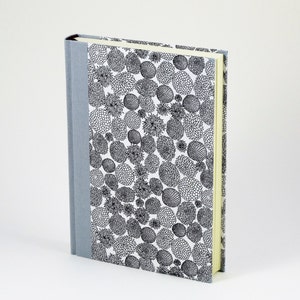 May include: A gray hardcover journal with a white cover featuring a black and white floral pattern.