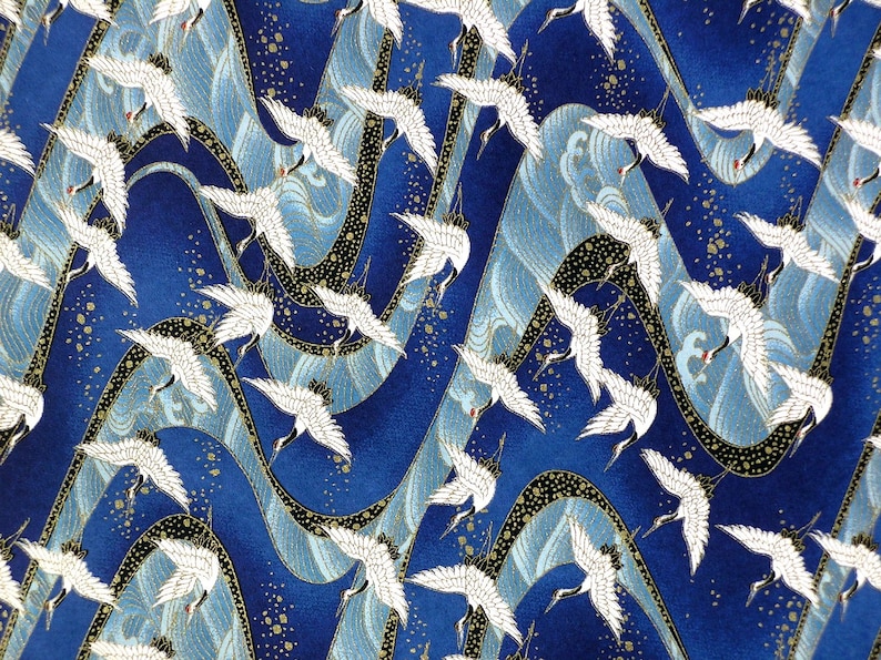 May include: A blue fabric with a repeating pattern of white cranes flying over stylized waves. The waves are a light blue and gold color. The background is a dark blue with gold flecks.