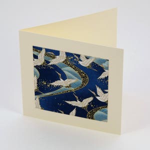 May include: A blank card with a cream-colored border and a blue and gold patterned insert featuring white cranes flying in a swirling pattern.