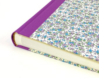 May include: A purple fabric-covered photo album with a floral pattern on the cover. The album is closed and the spine is visible.