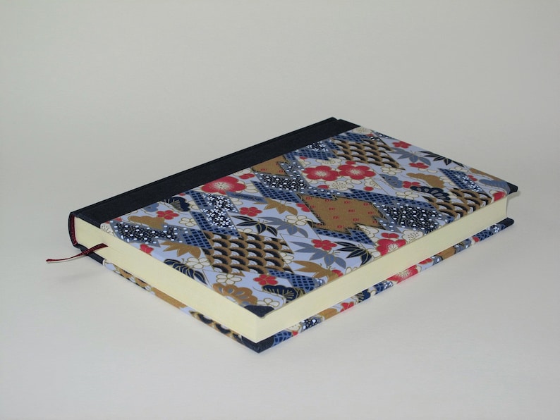 May include: A blue and gold patterned journal with a red bookmark. The cover is made of fabric with a Japanese-inspired design.