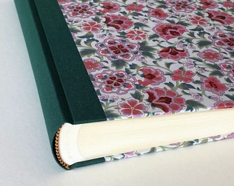 May include: A green fabric-covered photo album with a floral pattern on the cover. The album is closed and the spine is visible.