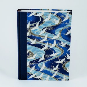 May include: A blue hardcover journal with a white crane and wave pattern on the cover. The journal has a dark blue spine.