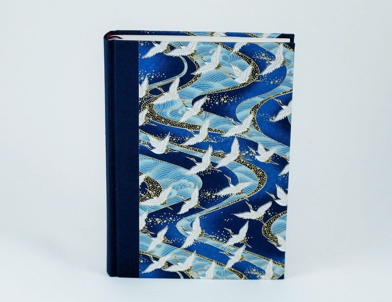 May include: A blue hardcover journal with a white crane and wave pattern on the cover. The journal has a dark blue spine.