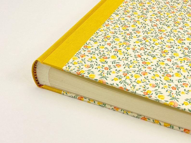 Puede incluir: Un &aacute;lbum de fotos amarillo con un patr&oacute;n floral en la portada. El &aacute;lbum tiene un borde amarillo alrededor de los bordes y est&aacute; cerrado.