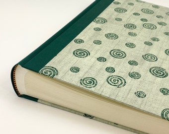 May include: A green and white photo album with a spiral pattern on the cover. The album has a gold-colored spine and is closed.