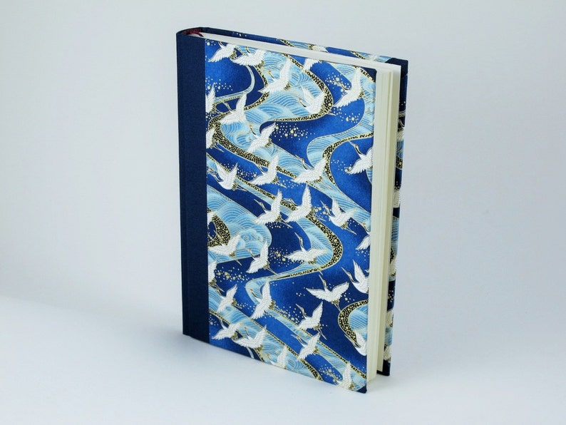 May include: A blue and white journal with a pattern of white cranes flying over blue waves. The journal has a dark blue spine and a white cover.