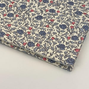May include: A close-up of a notebook with a floral pattern. The cover is white with blue and pink flowers.