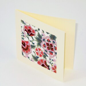 Puede incluir: Una tarjeta en blanco con un fondo de color crema y un dise&ntilde;o floral en el frente. El dise&ntilde;o floral est&aacute; en tonos de rosa, rojo y azul.