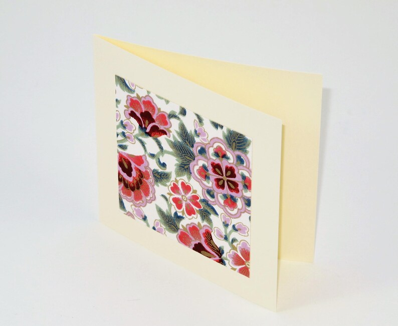 Puede incluir: Una tarjeta en blanco con un fondo de color crema y un dise&ntilde;o floral en el frente. El dise&ntilde;o floral est&aacute; en tonos de rosa, rojo y azul.