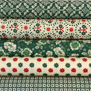 Può includere: Una pila di rotoli di tessuto con vari motivi. Il rotolo superiore presenta un motivo floreale verde scuro e bianco. Altri rotoli mostrano motivi floreali e geometrici rossi, verdi e bianchi. I tessuti sembrano essere di cotone o un materiale simile.